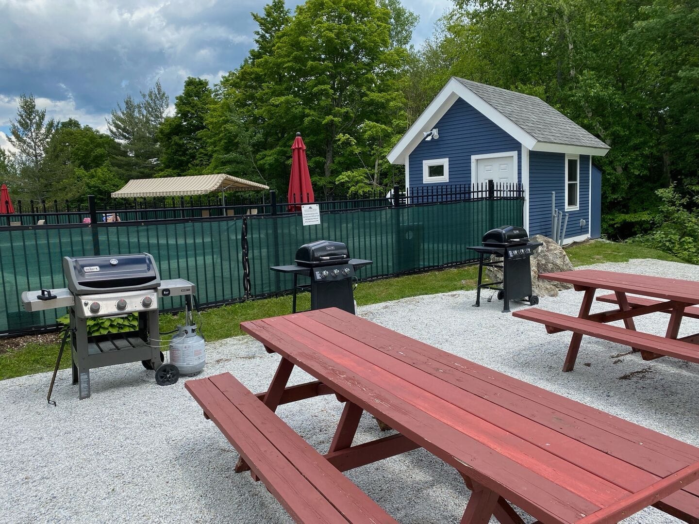 Outdoor grilling and dining area with covered picnic pavilion adjacent to heated pool at Mountain Green Resort amenities