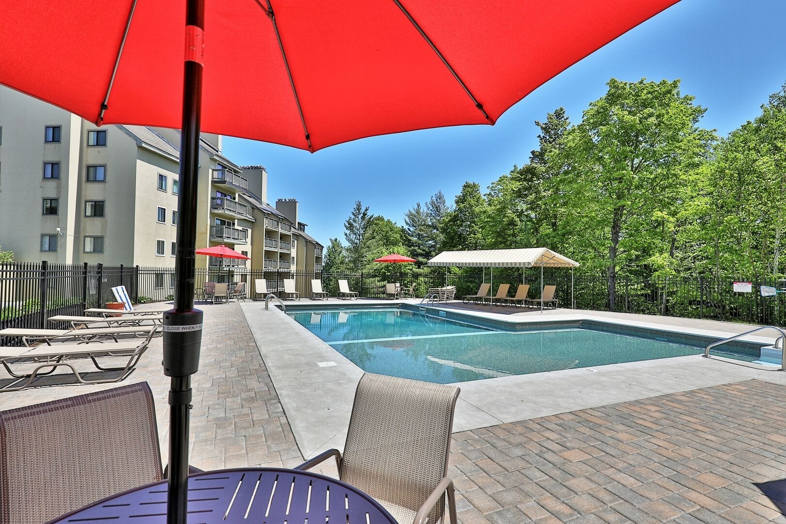 Heated outdoor saltwater swimming pool with red patio umbrellas, lounge chairs, and mountain views at Mountain Green Resort Killington
