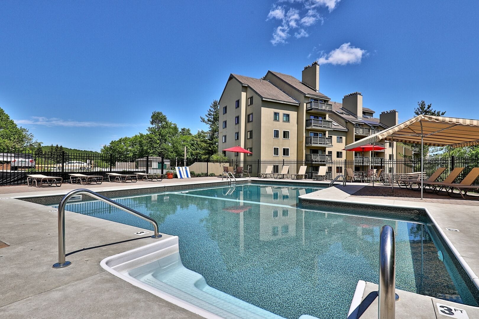 Outdoor pool area with nearby hot tub, BBQ grills, fire pit, and Killington mountain views