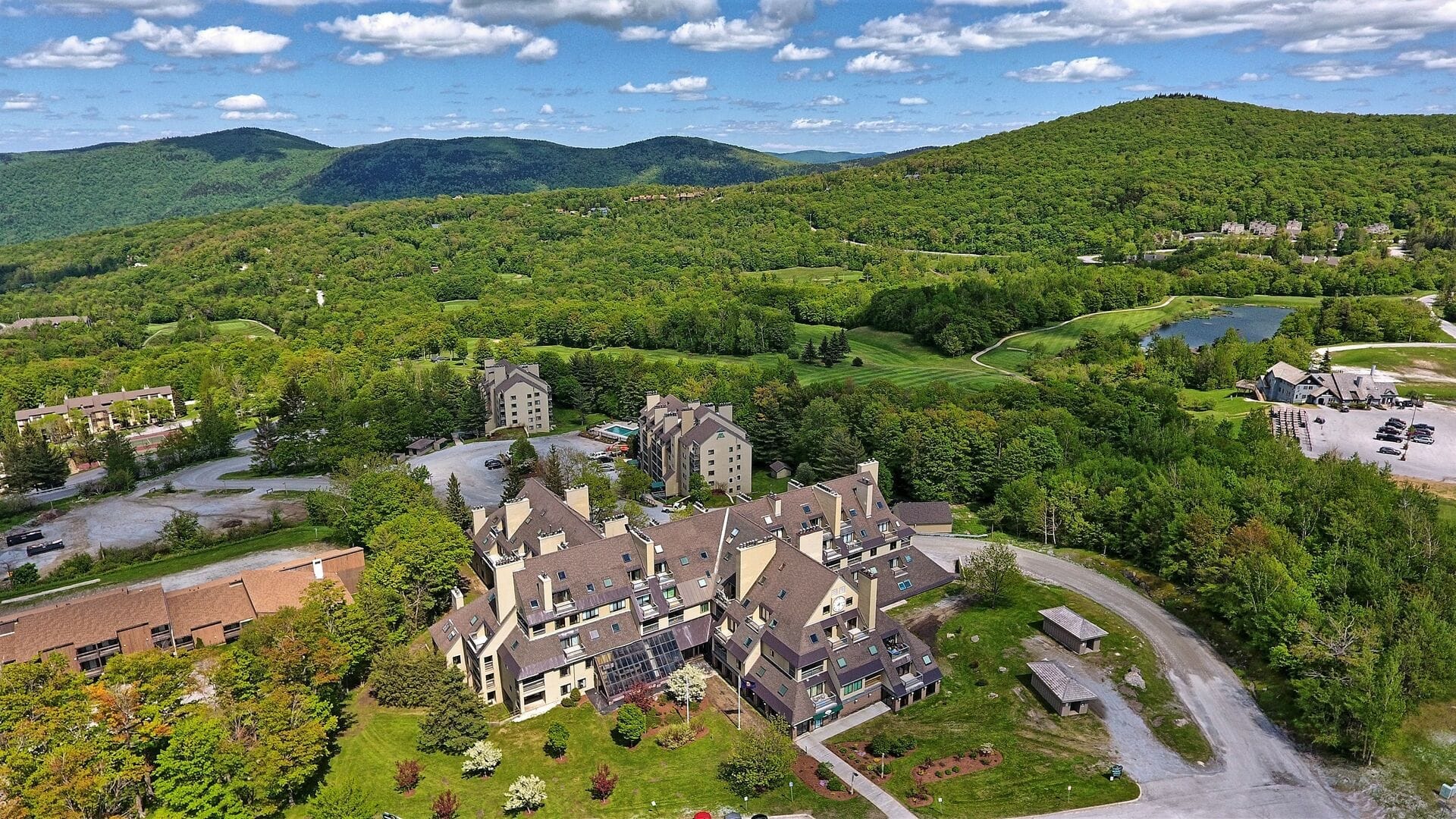 Drone view of Mountain Green condos with golf course, pond, and summer Vermont landscape